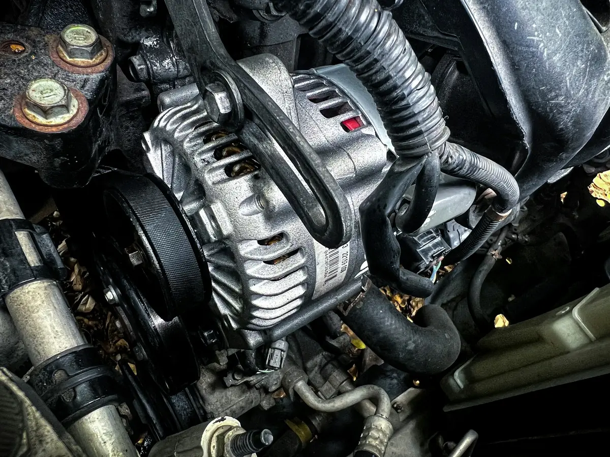An alternator and drive belt in an engine bay
