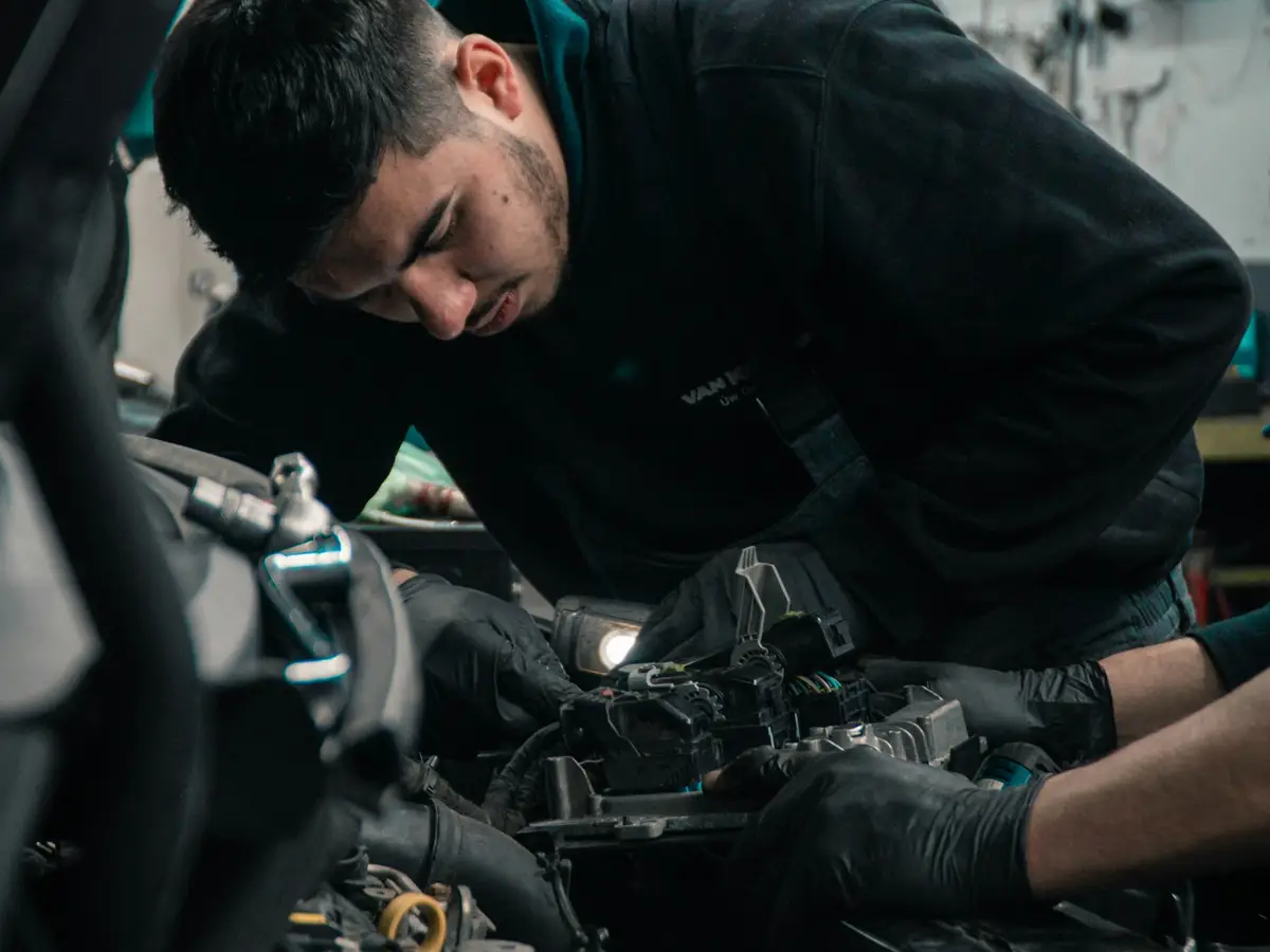 A mechanic in gloves carrying out a repair by hand
